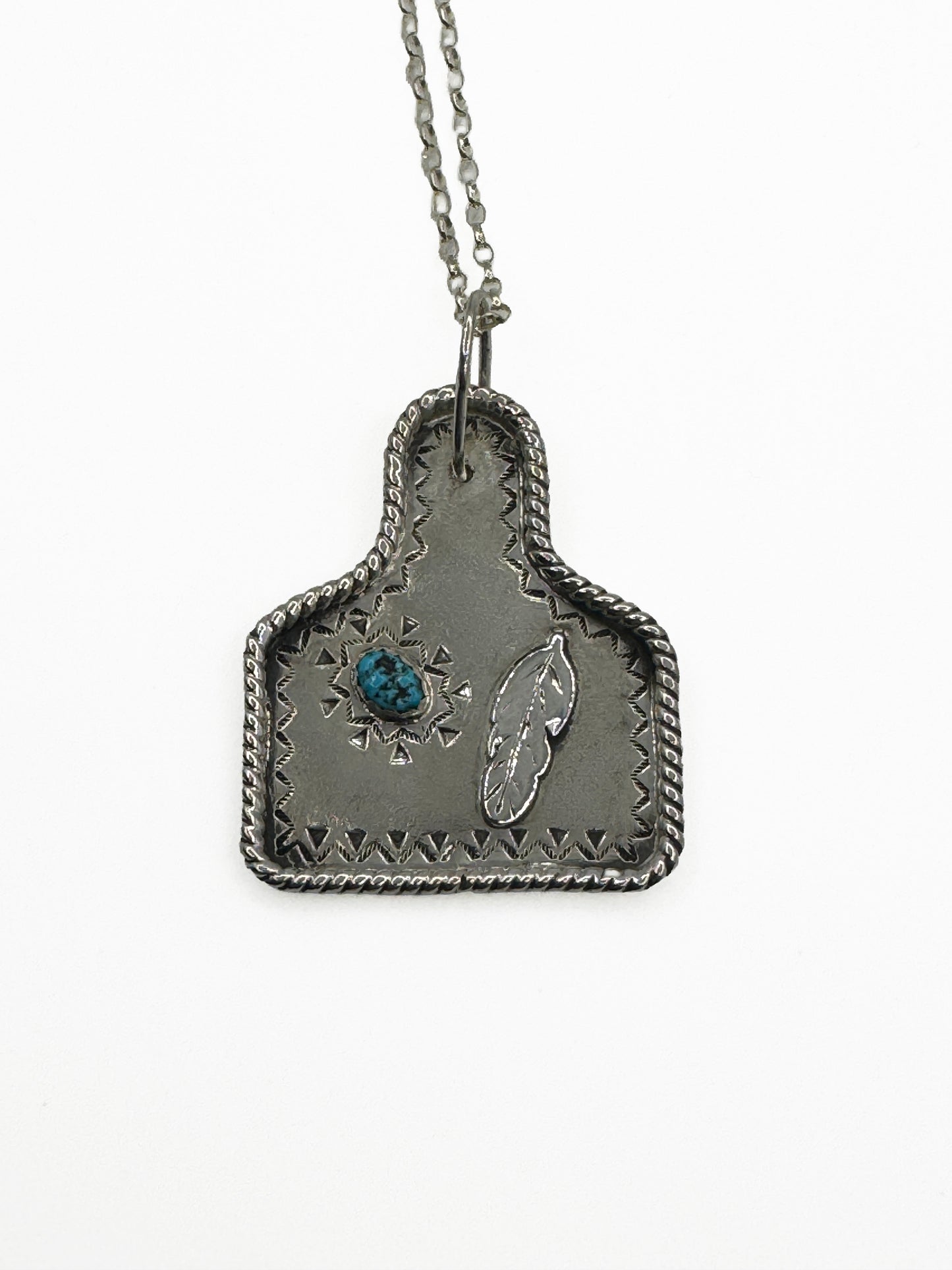 Cow Tag Pendant with Kingman Turquoise and feather to the righ